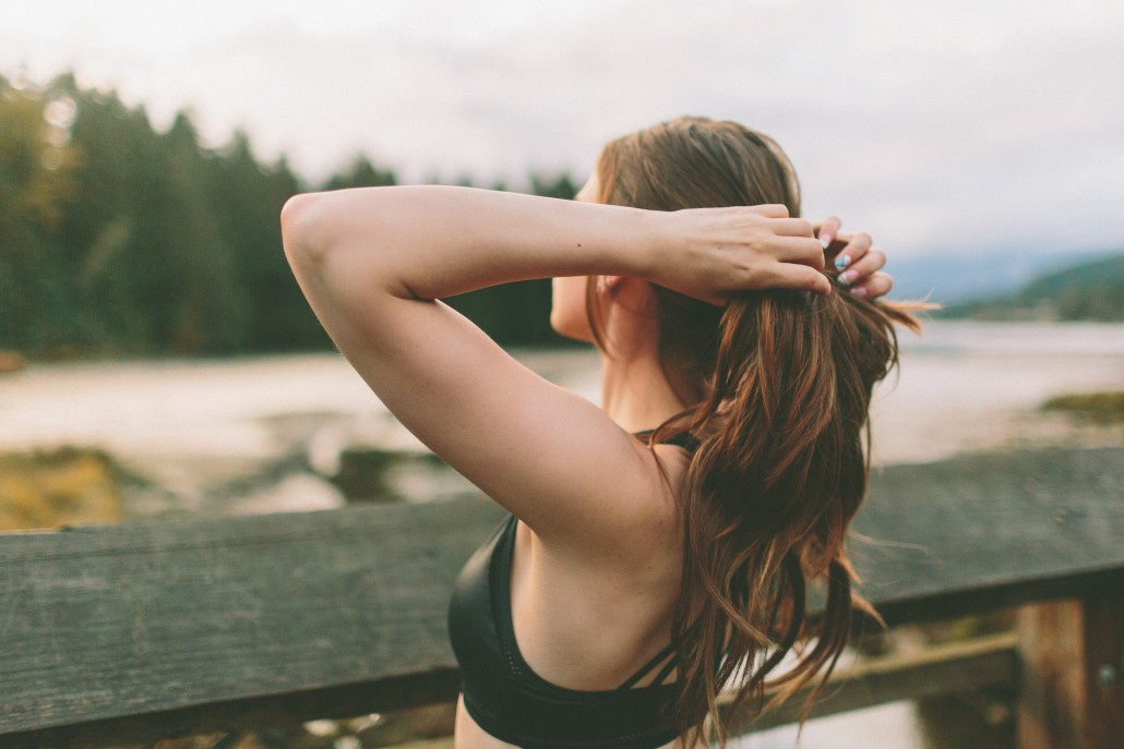 A woman in a sports bra adjusts her hair